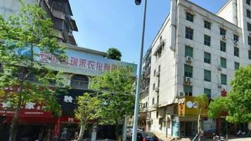 A street view with buildings, trees, and parked cars.
