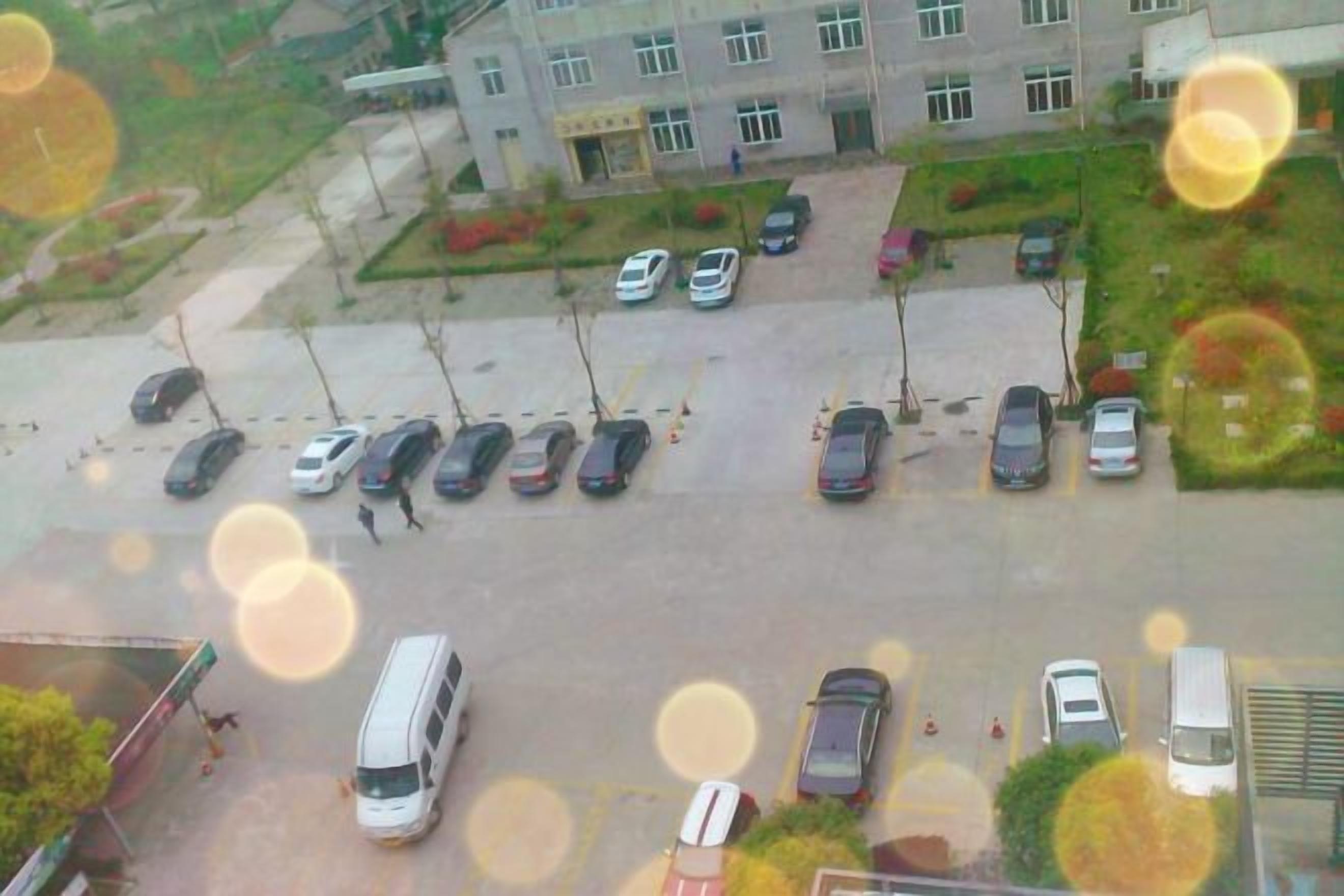 A parking lot with multiple cars and a bus, surrounded by buildings.