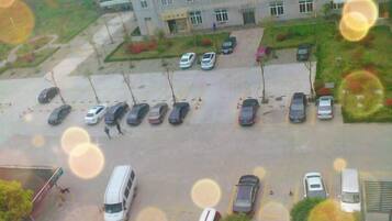 A parking lot with multiple cars and a bus, surrounded by buildings.