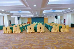 A conference room with rows of chairs, tables, and a stage. - Anqing Yingdeli Hotel (Anqing)