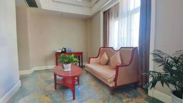 A room with a beige sofa, a small round table with a plant, and a decorative ceiling.