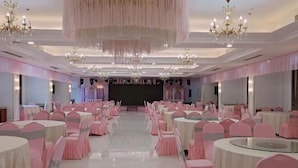 A banquet hall with round tables and chairs, chandeliers, and a stage. - Anqing Yingdeli Hotel (Anqing)
