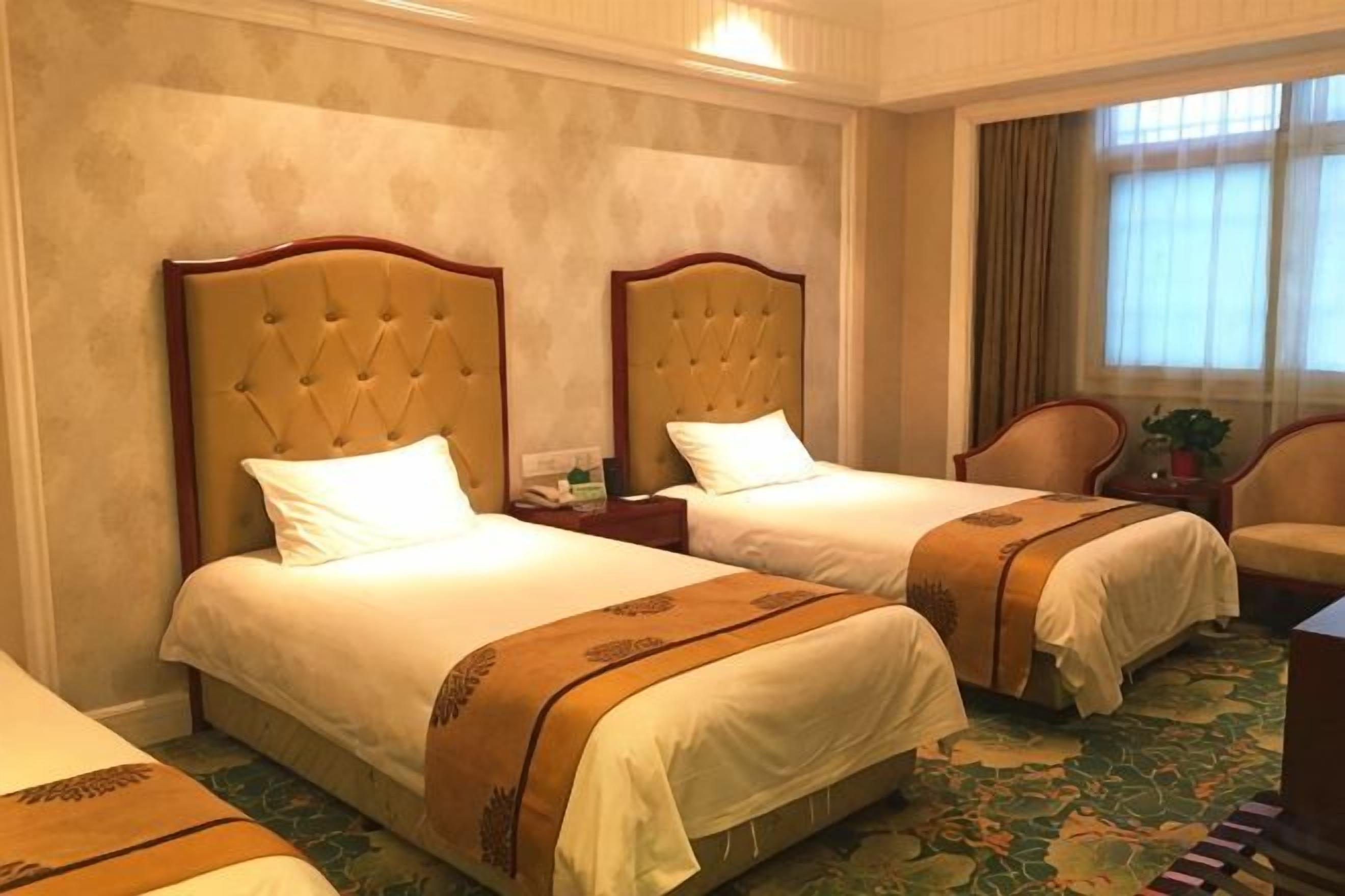 A hotel room with two beds, a sitting area, and a view of the outdoors.