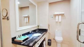 Une salle de bain avec un comptoir en marbre, un lavabo, des toilettes et un miroir.