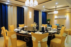 A conference room with a round table, chairs, and a chandelier.