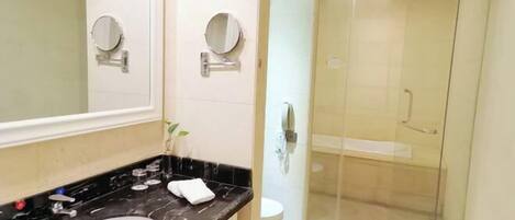 A bathroom with a white sink, black countertop, and a glass-enclosed shower.
