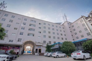 A multi-story building with a central entrance, several parked cars, and a clear sky. - Anqing Yingdeli Hotel (Anqing)