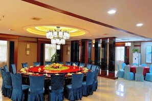 A large round dining table with chairs, a chandelier, and a floral centerpiece.