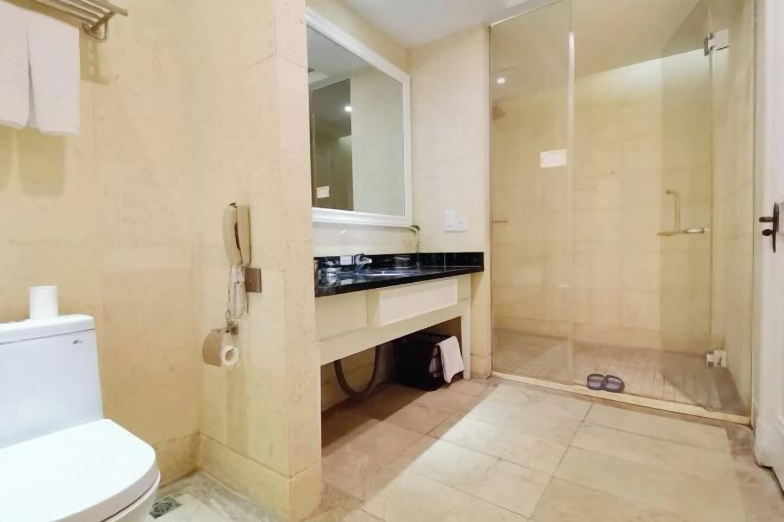 Un baño con inodoro, lavamanos, espejo y cabina de ducha.
