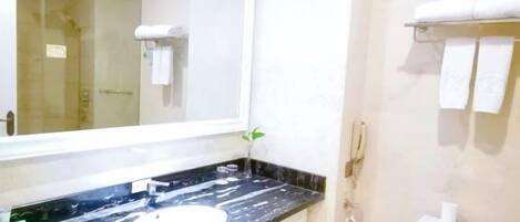 A bathroom with a large mirror, a black countertop, a toilet, and a towel rack.