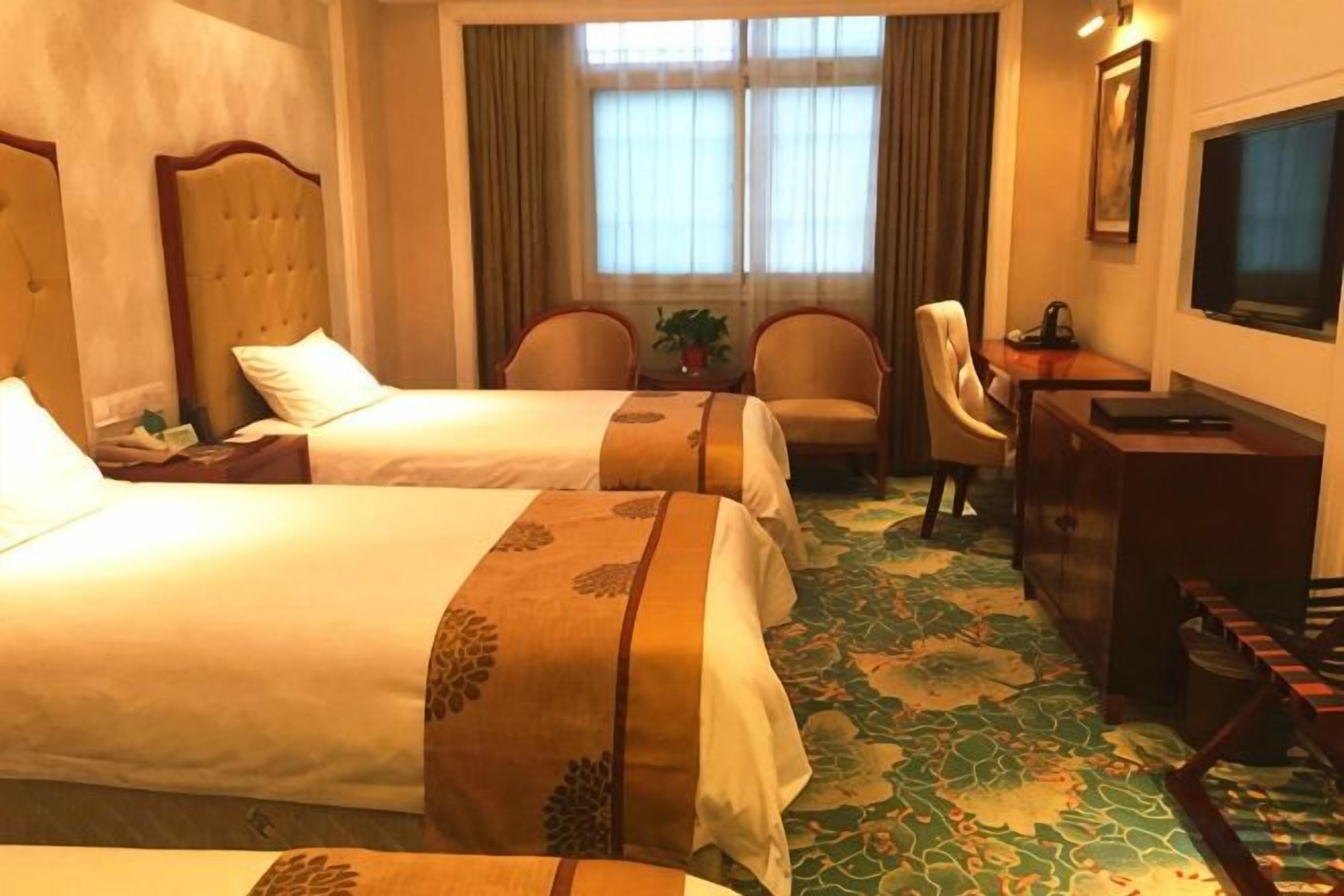 Una habitación de hotel con dos camas, un escritorio, una silla y un televisor.
