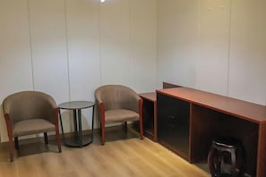 A room with two wooden chairs, a small round table, and a wooden cabinet.