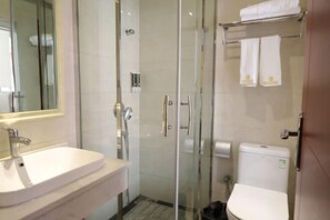 Un baño moderno con cabina de ducha de vidrio, un lavamanos blanco y un inodoro.
