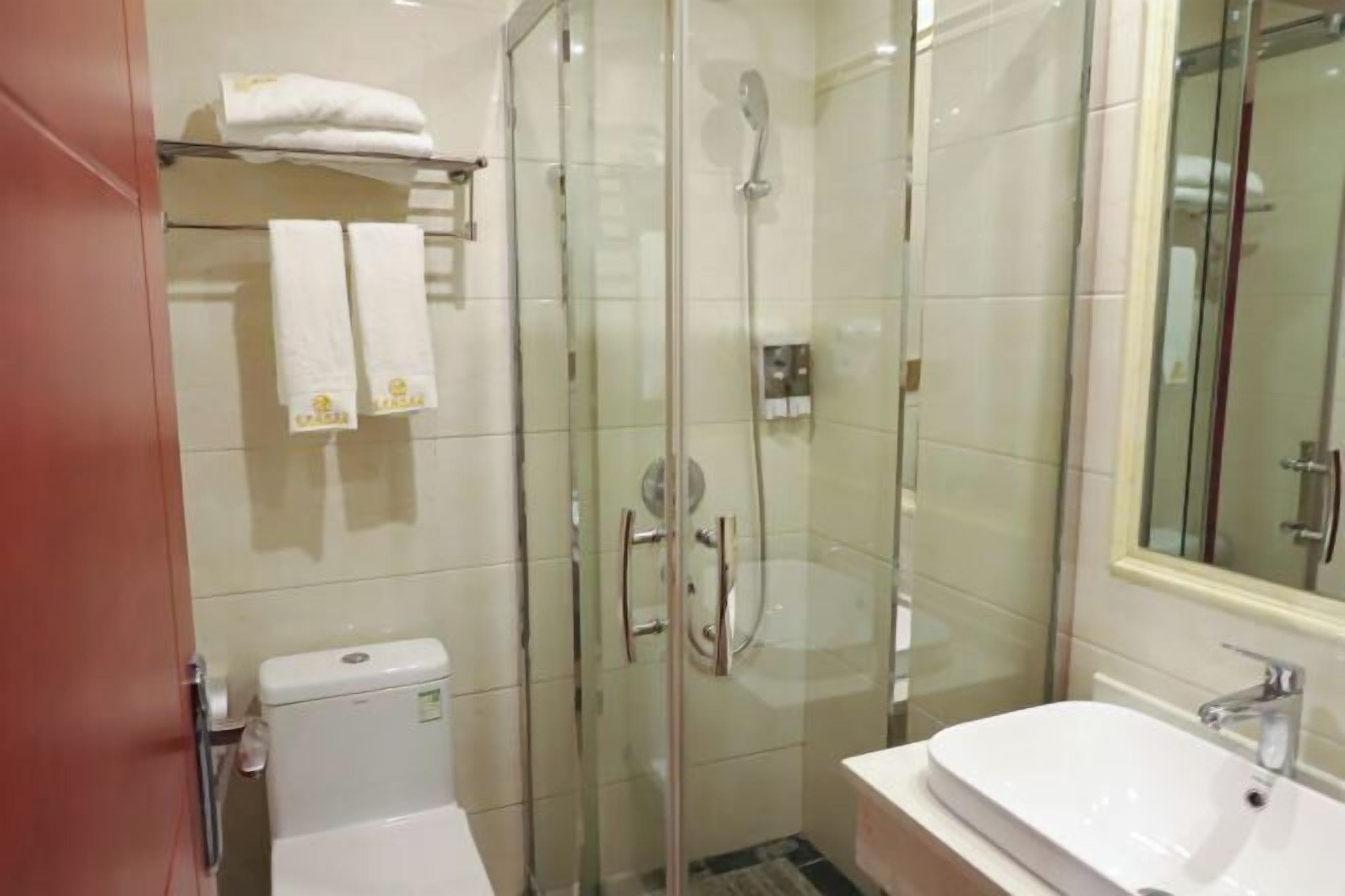 Une salle de bain moderne avec une douche à parois de verre, un lavabo blanc et des toilettes.