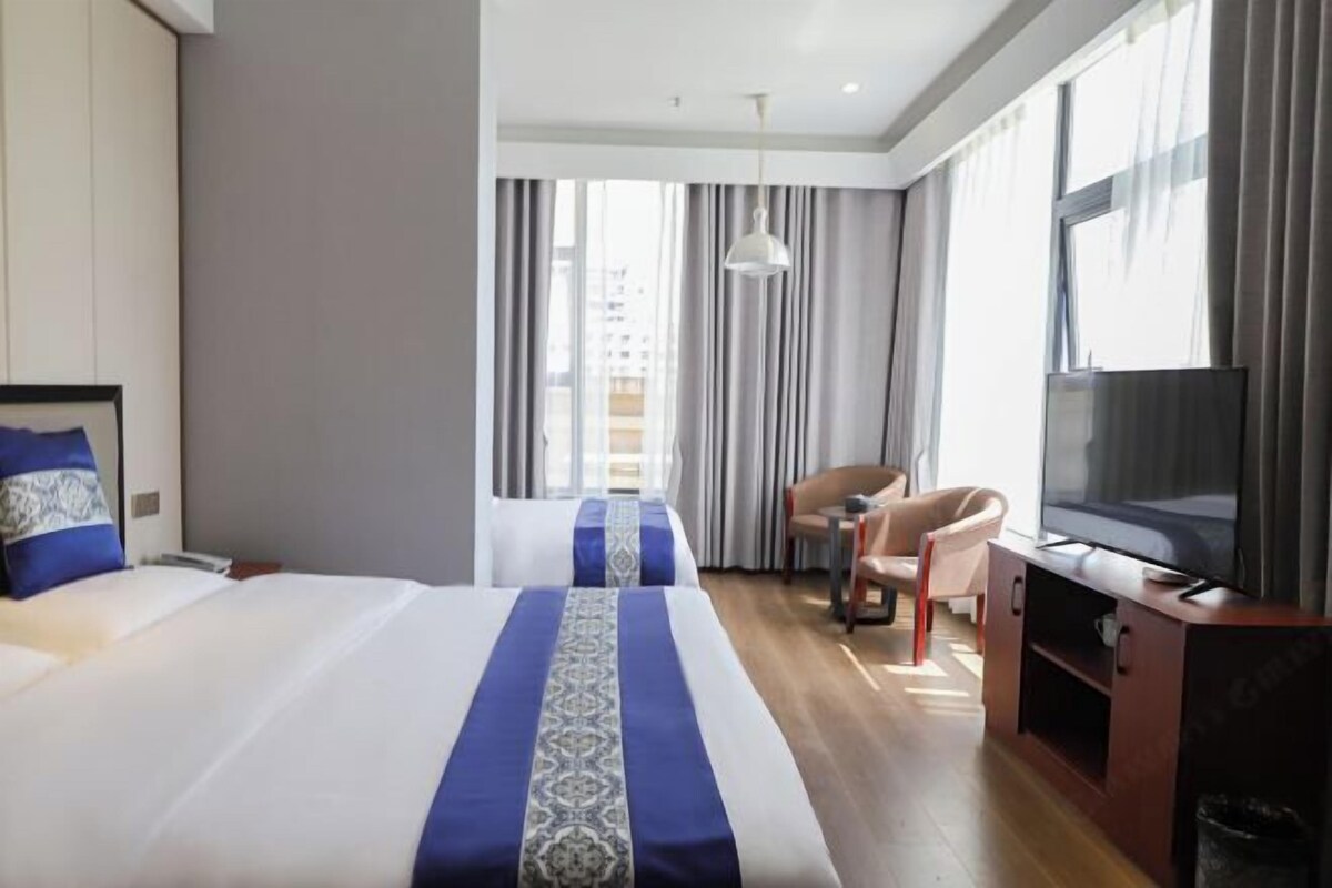 Habitación de hotel con dos camas, televisión, escritorio y silla.
