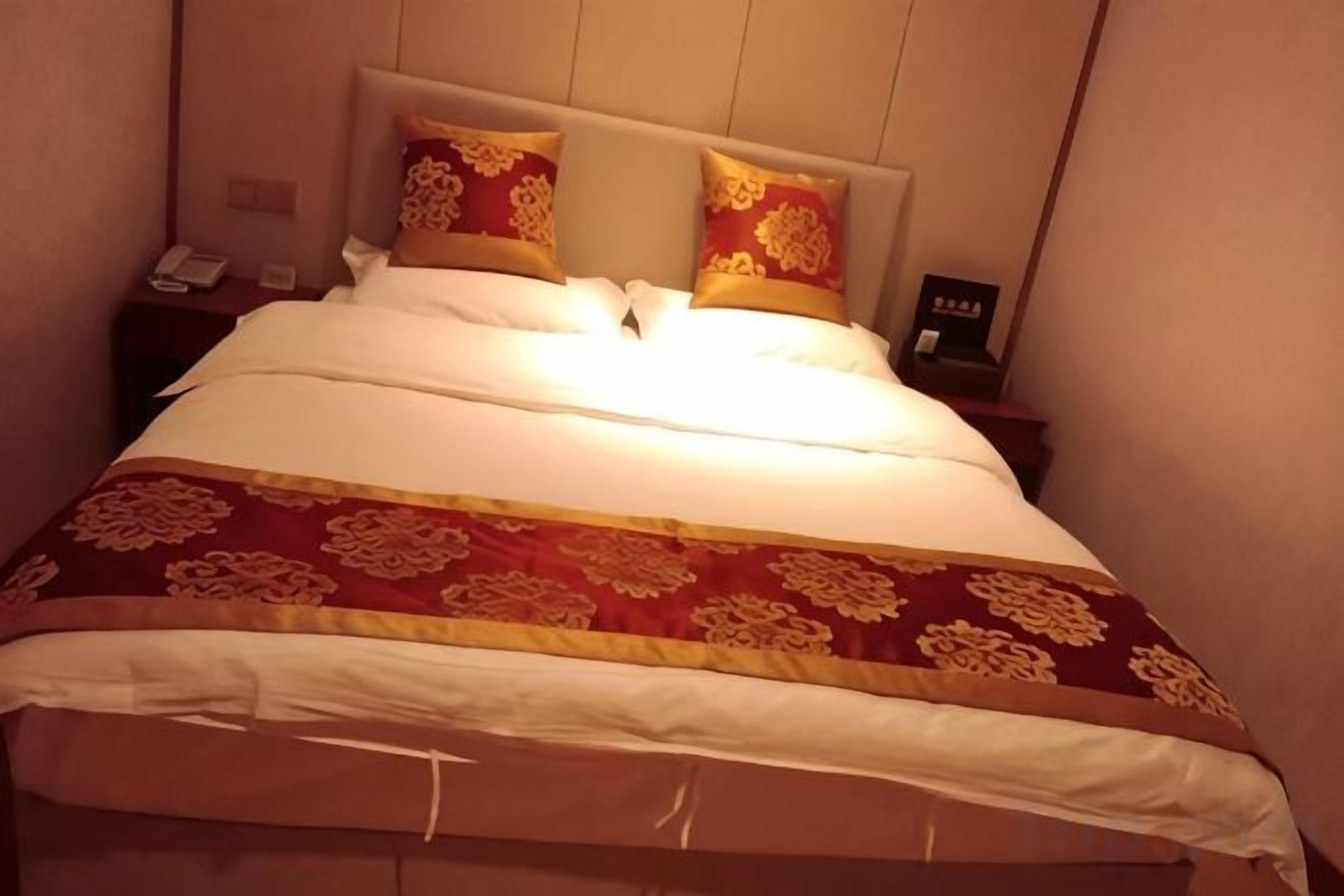 Une chambre d’hôtel avec un lit, deux oreillers, une table de chevet et un téléphone.