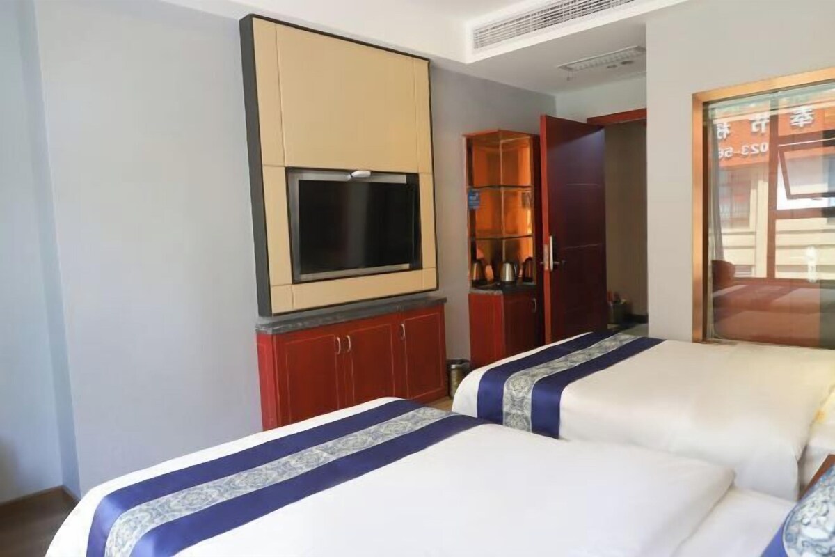 Una habitación de hotel con dos camas, un televisor montado en la pared y un minibar.