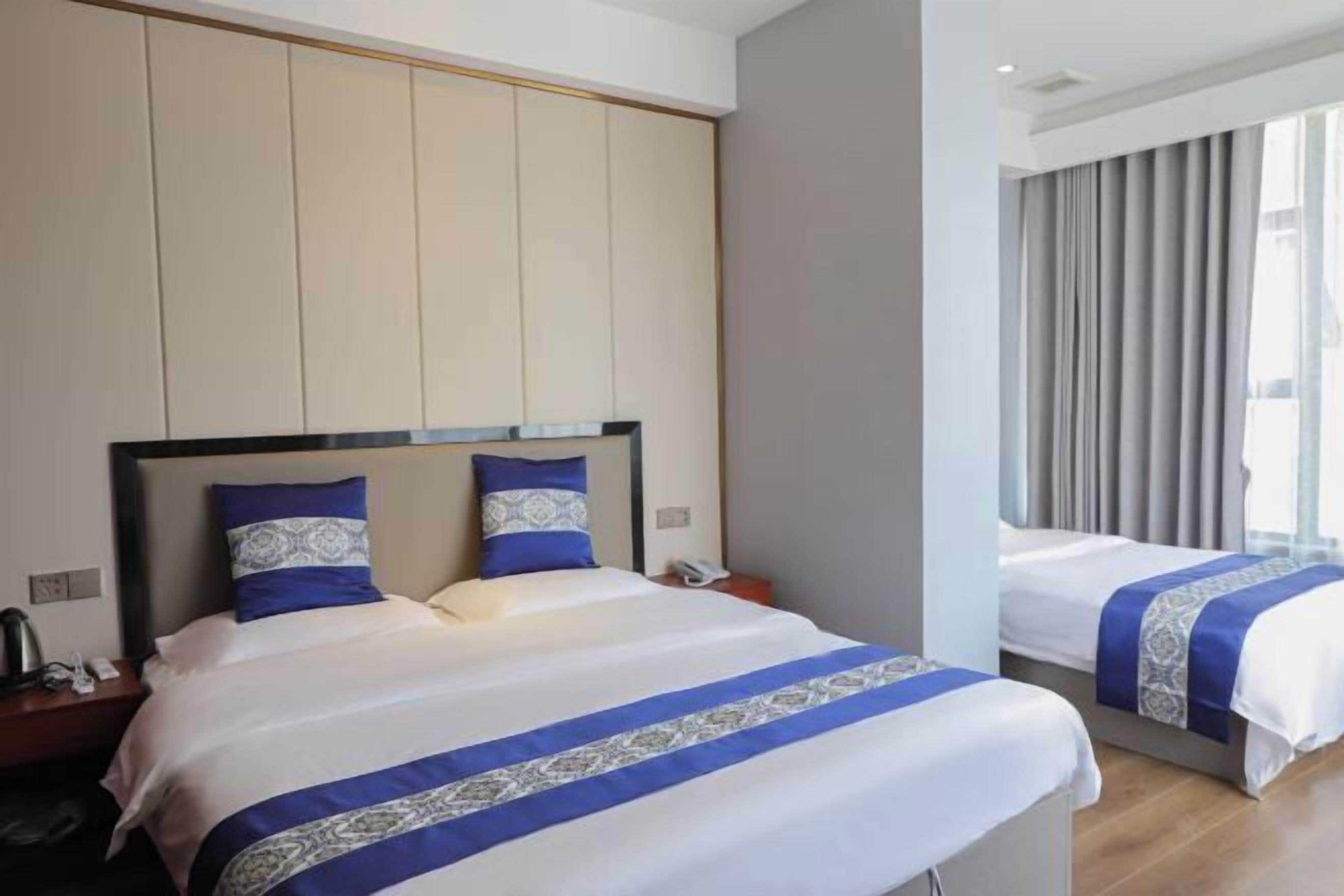 A hotel room with a large bed, a smaller bed, and a nightstand with a phone and a lamp.