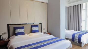 A hotel room with a large bed, a smaller bed, and a nightstand with a phone and a lamp.