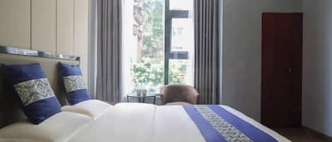 A hotel room with a large bed, a small table, and a wardrobe.