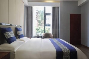 Una habitación de hotel con una cama grande, una mesita pequeña y un armario.