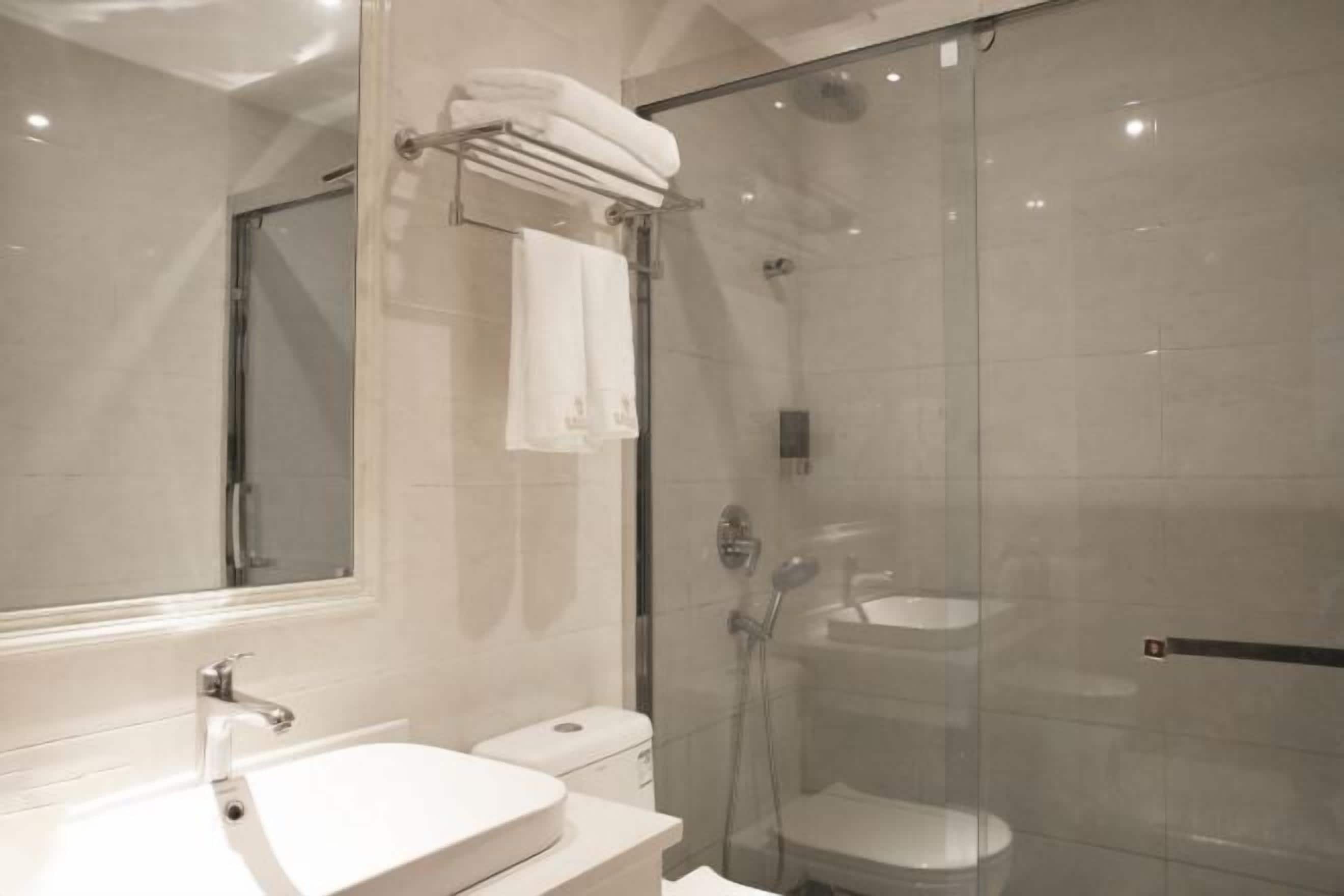 A modern bathroom with a glass-enclosed shower, a white sink, and a large mirror.