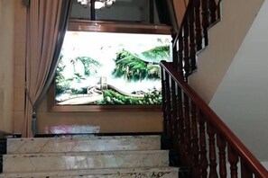 Stunning views of the lush landscape unfold from the large window, with a bridge and trees visible in the distance.