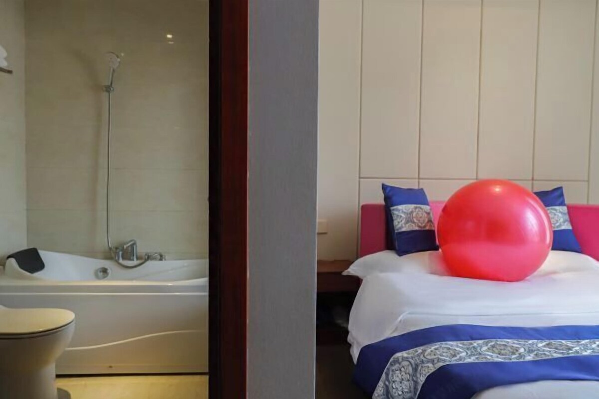 Un baño moderno con bañera y ducha, y un dormitorio con cama, almohadas y un globo rojo.