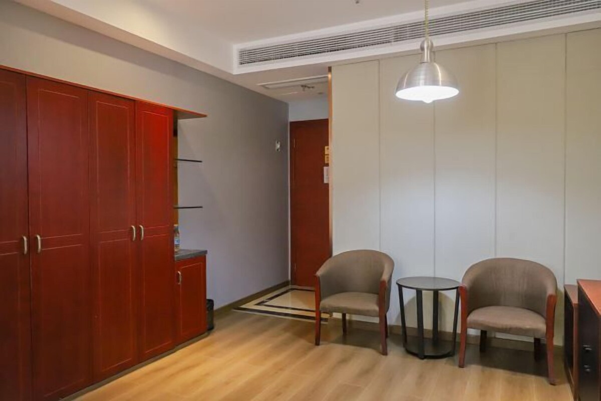 Una habitación con un armario de madera, dos sillas, una mesita redonda y una lámpara colgante.