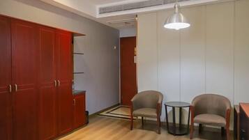 A room with a wooden wardrobe, two chairs, a small round table, and a pendant light.
