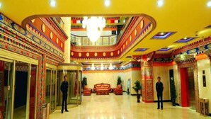 Un hall d’hôtel avec un grand escalier, un lustre et un comptoir d’accueil.