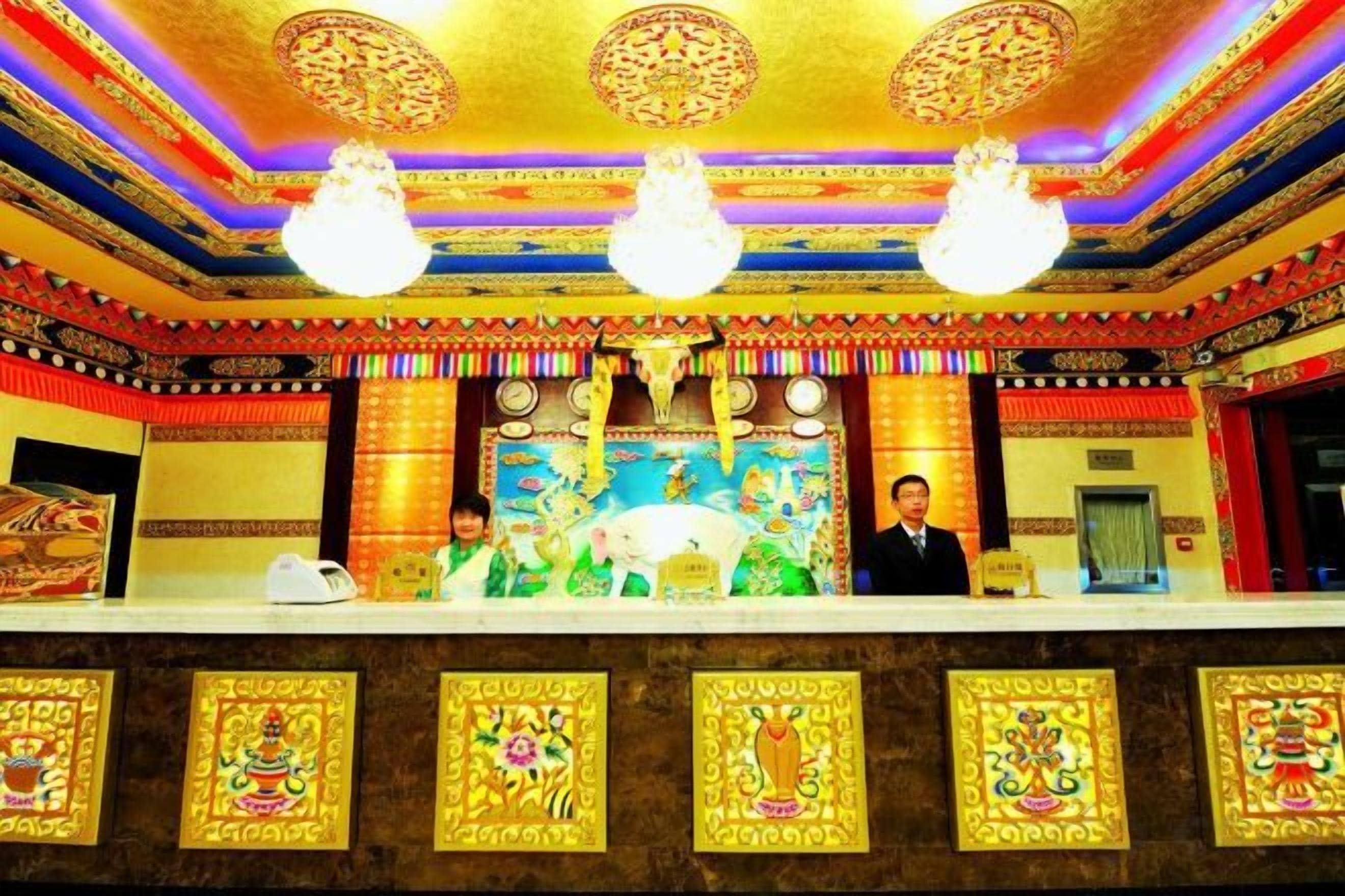 A reception area with a counter, a large painting, and a chandelier.