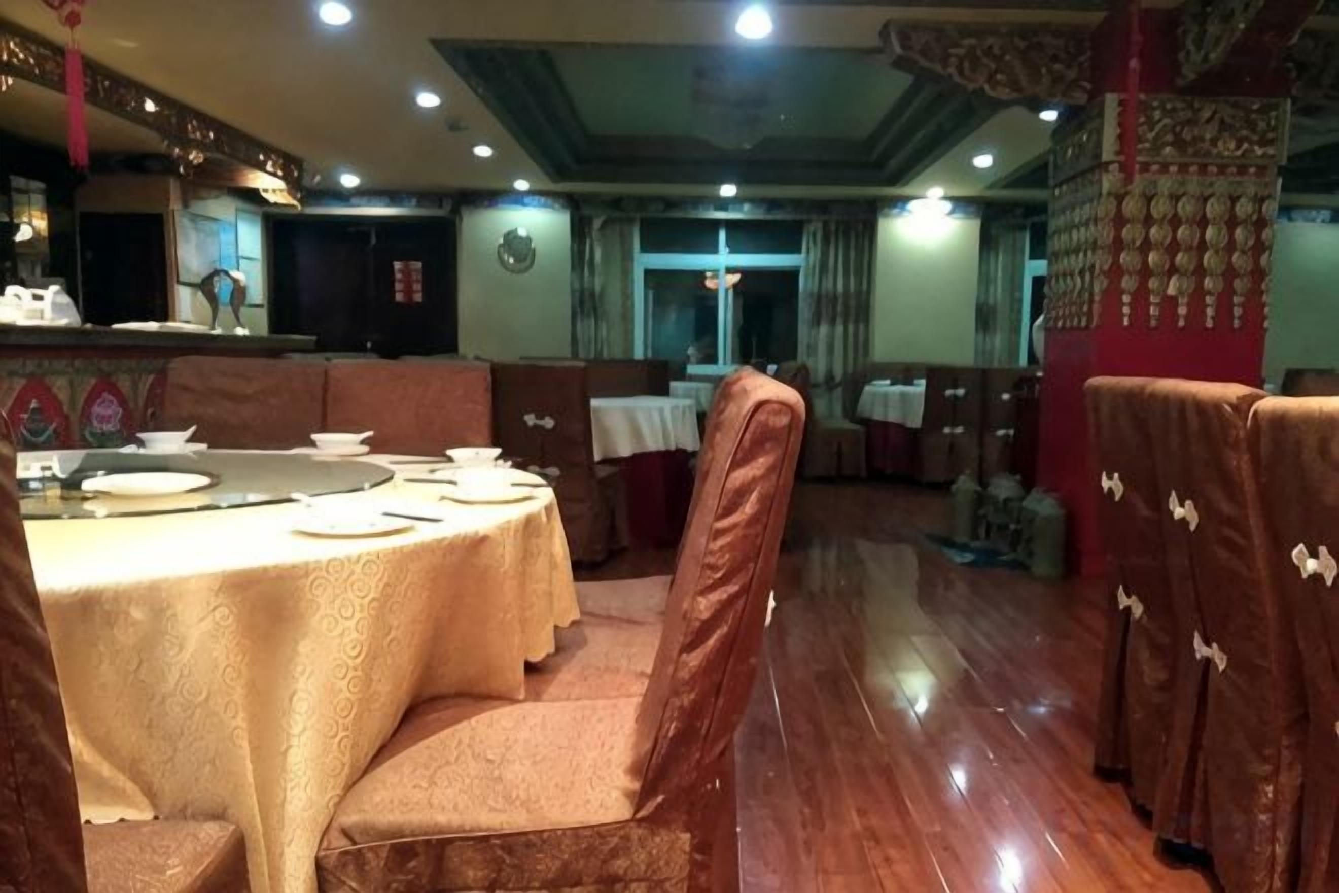A restaurant with a round table set for dining, cushioned chairs, and a bar area in the background.