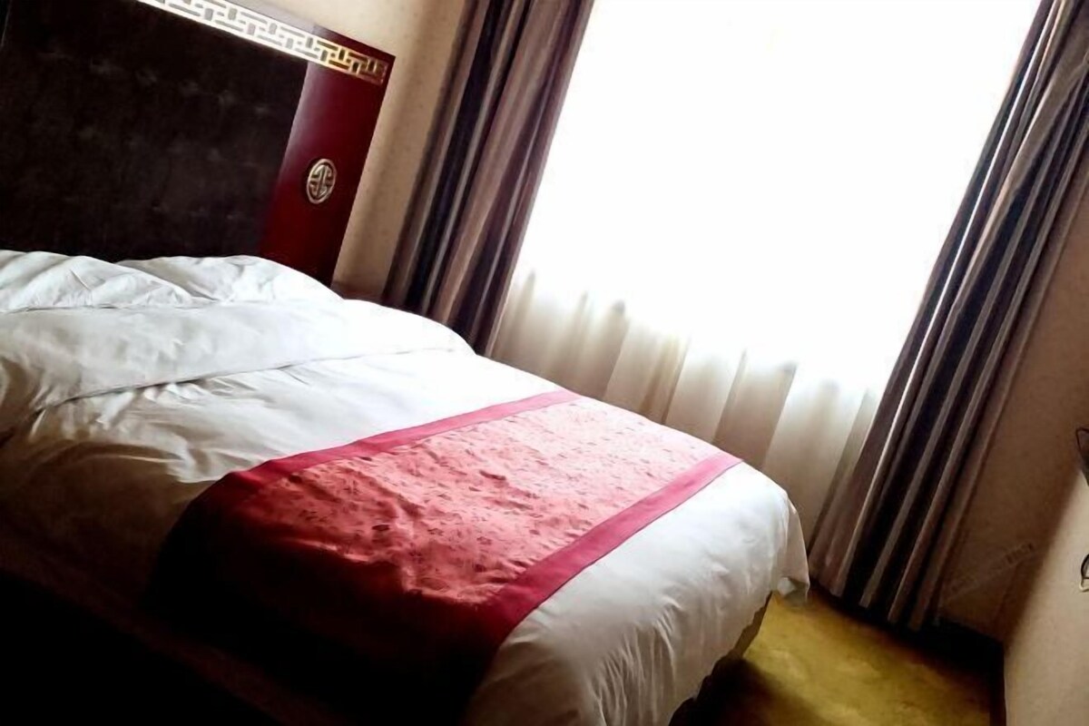 Une chambre d’hôtel avec un lit, des rideaux et une fenêtre.