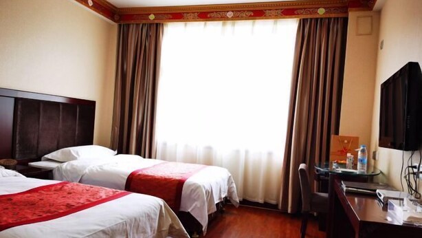 Une chambre d’hôtel avec deux lits, un bureau, une chaise et un téléviseur.