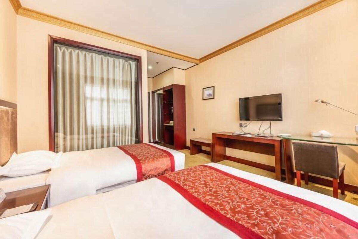 Une chambre d’hôtel avec deux lits, un bureau, une télévision et un miroir.