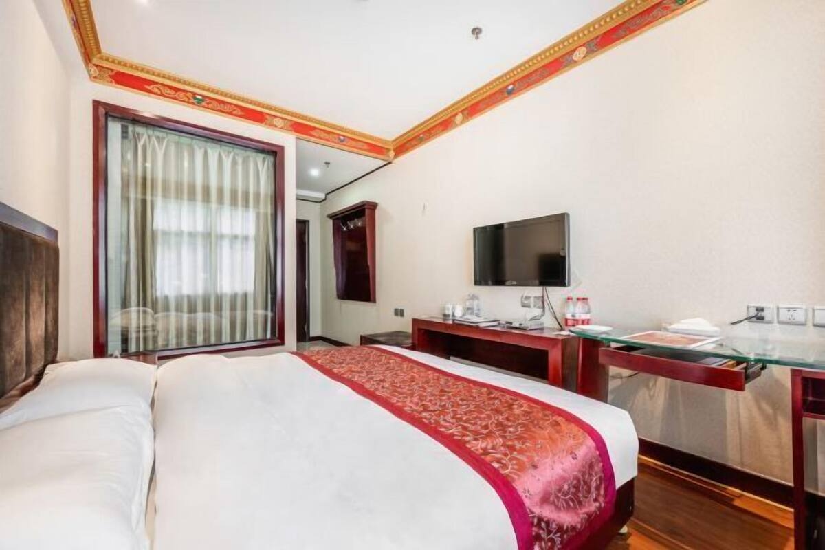 Habitación de hotel con una cama grande, un escritorio y un televisor de pantalla plana, además de una ventana con cortinas.