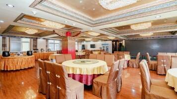A banquet hall with round tables and chairs, chandeliers, and a stage.
