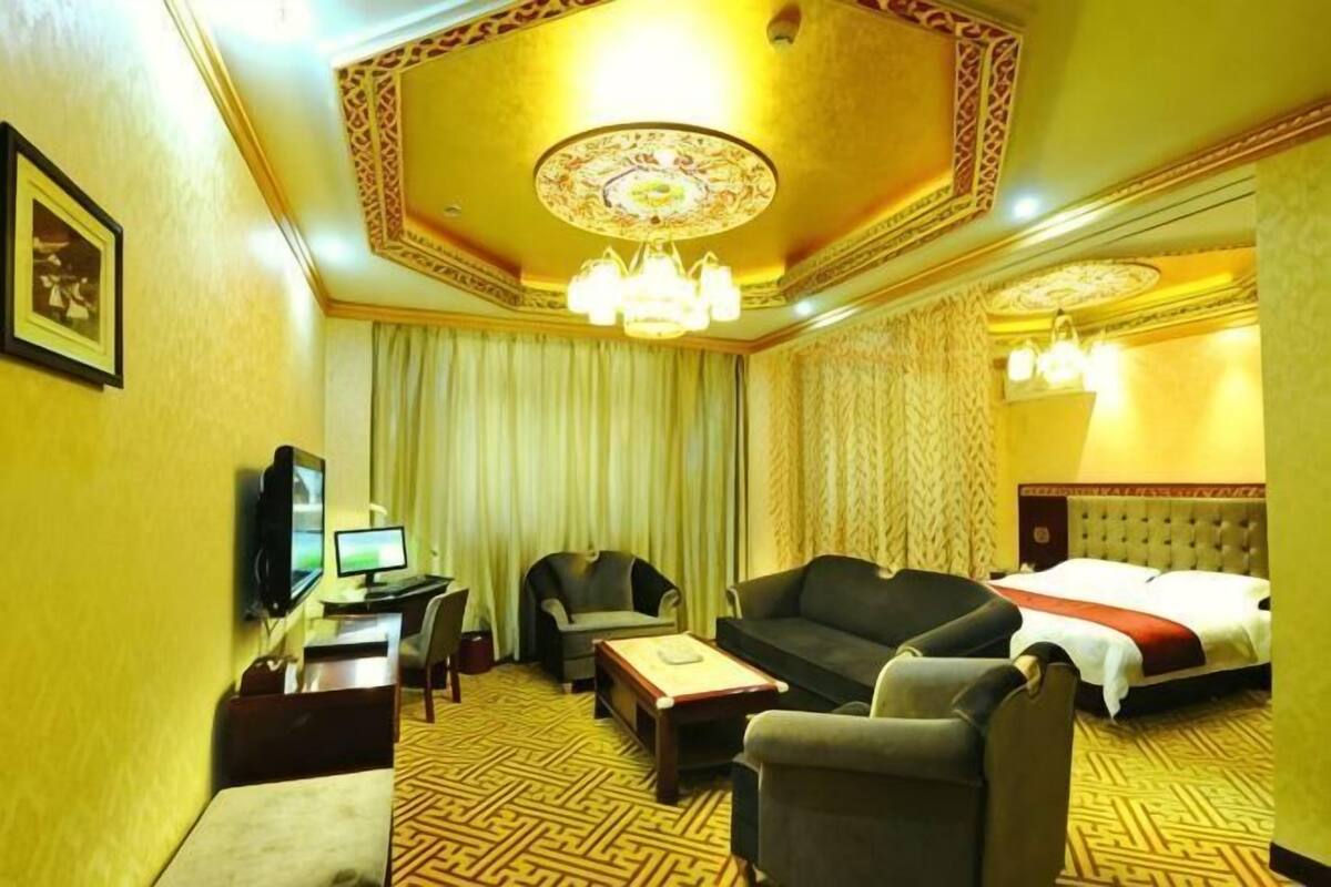Habitación de hotel con sofá, cama, escritorio con computadora, silla y televisión.