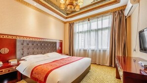 Une chambre d’hôtel avec un grand lit, un bureau, une télévision et une fenêtre avec des rideaux.