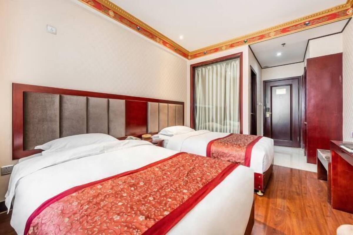 Habitación de hotel con dos camas, cabecero de madera, escritorio y armario.