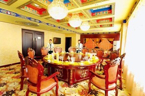 Une salle de conférence avec une table ronde, des chaises et un lustre.