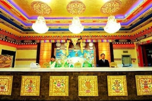 A reception area with a marble counter, two chandeliers, and a large mural. - Labuleng Civil Aviation Hotel (Xiahe)