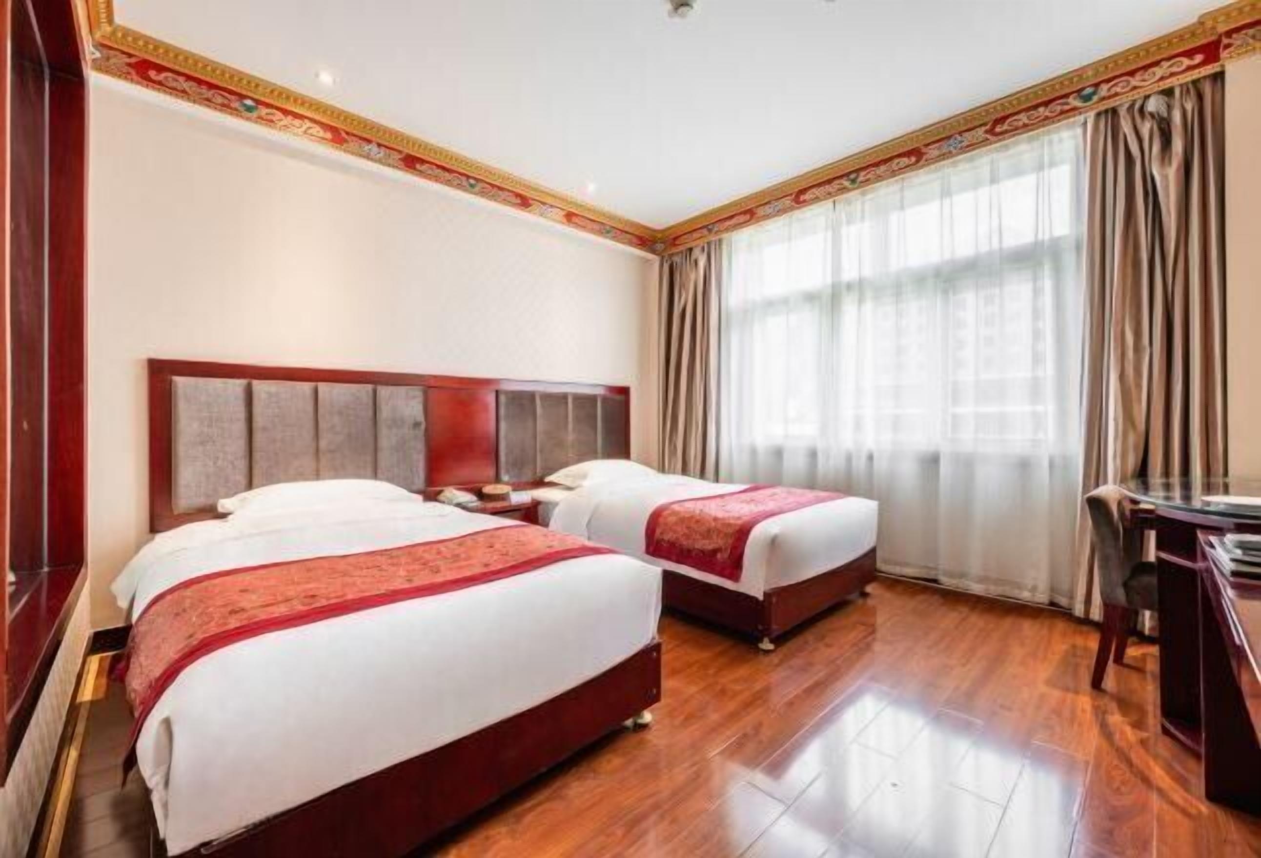 Habitación de hotel con dos camas, piso de madera y un escritorio con silla.