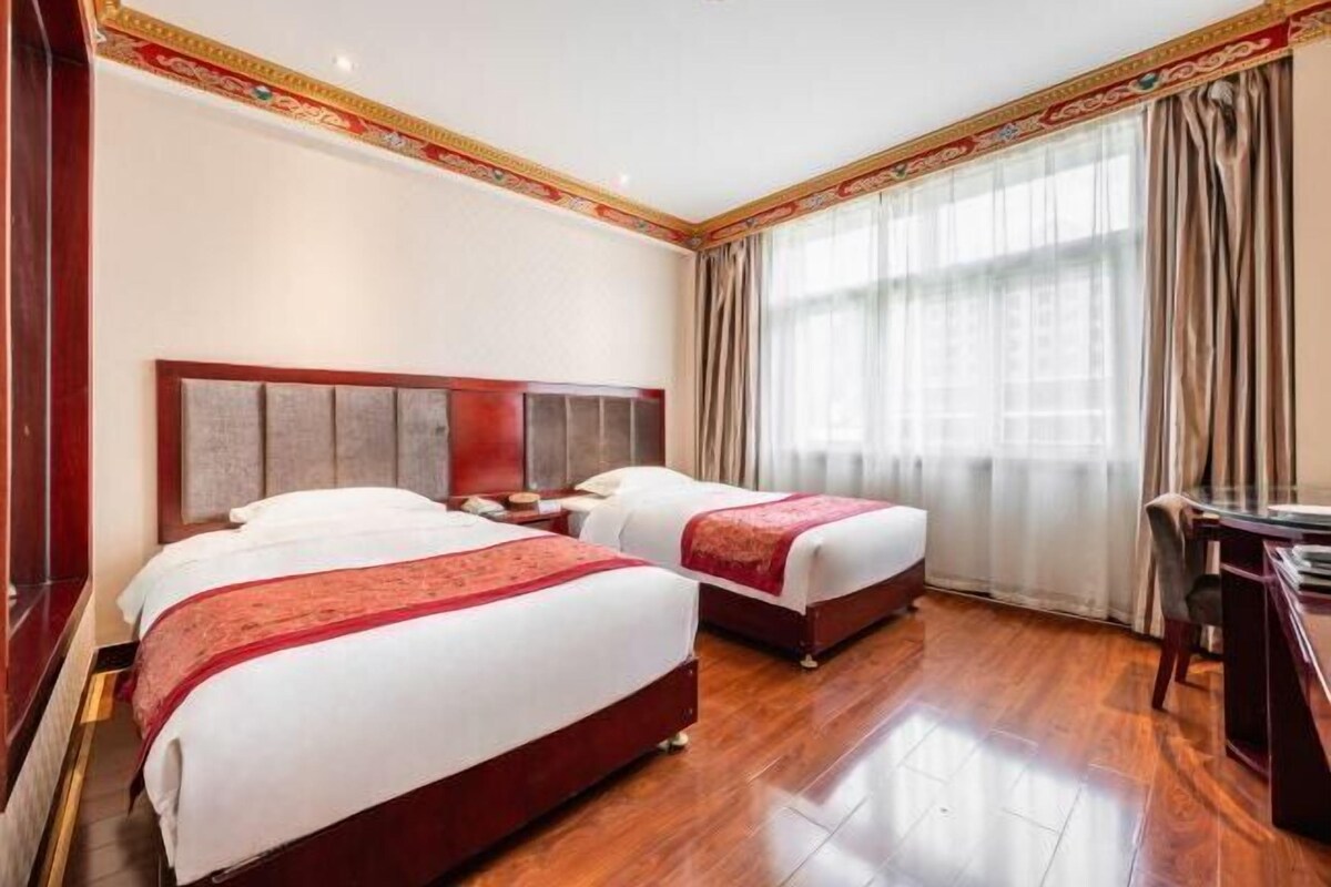Une chambre d’hôtel avec deux lits, un plancher en bois et un bureau avec une chaise.