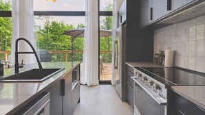 A modern kitchen with a large island, stainless steel appliances, and a view of the outdoors.