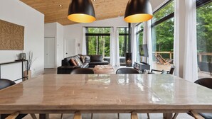 A modern interior with a large wooden dining table, leather seating, and pendant lighting.