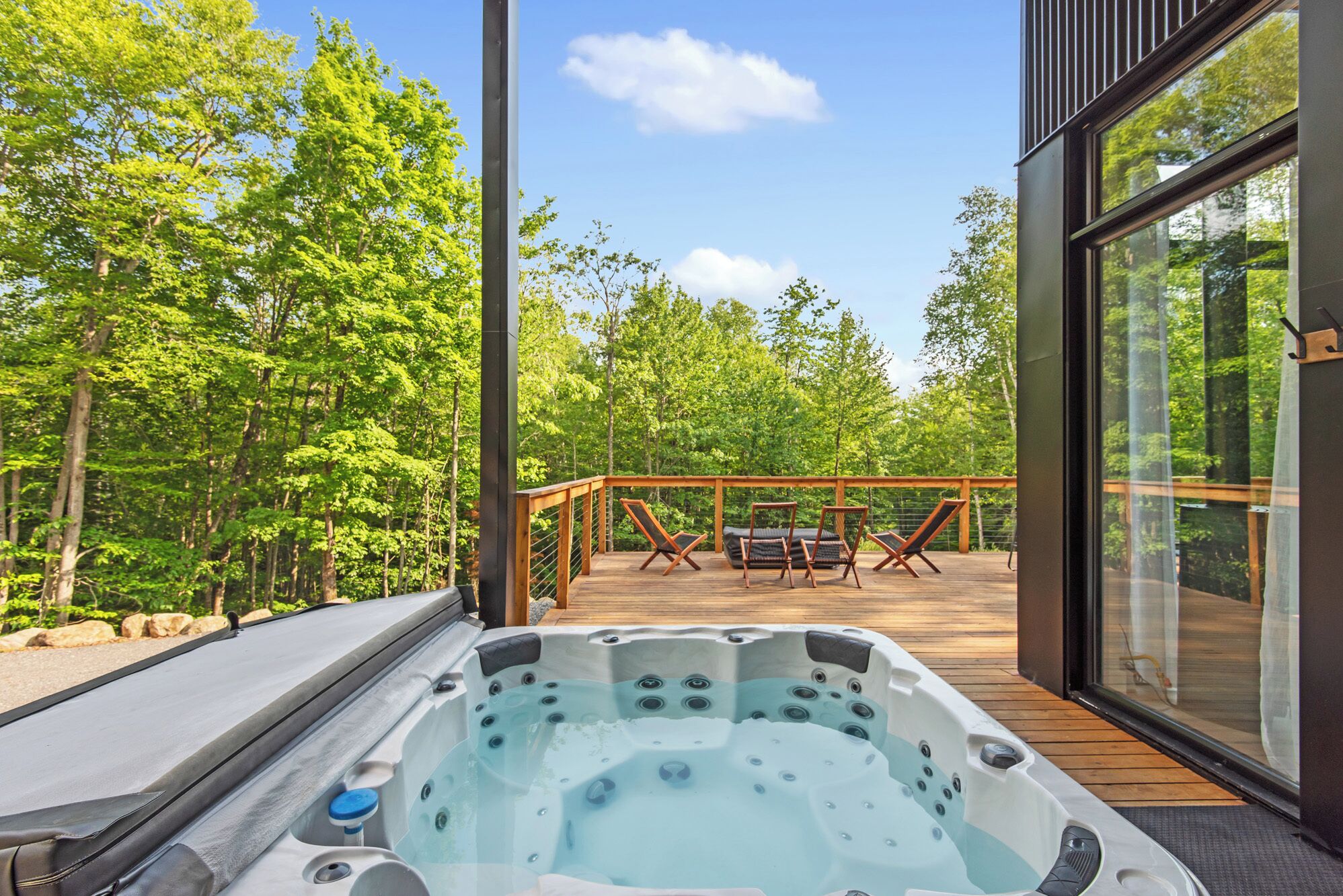 Un jacuzzi en una terraza de madera con vista a un bosque.