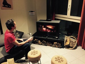 Una persona sentada en un sofá en una habitación con chimenea, una ventana y un letrero en la pared.