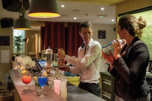 A bar area with a bartender preparing drinks, a polar bear decoration, and various bottles and glasses on the counter. - Club Les Alpes Dazur (La Salle-les-Alpes)